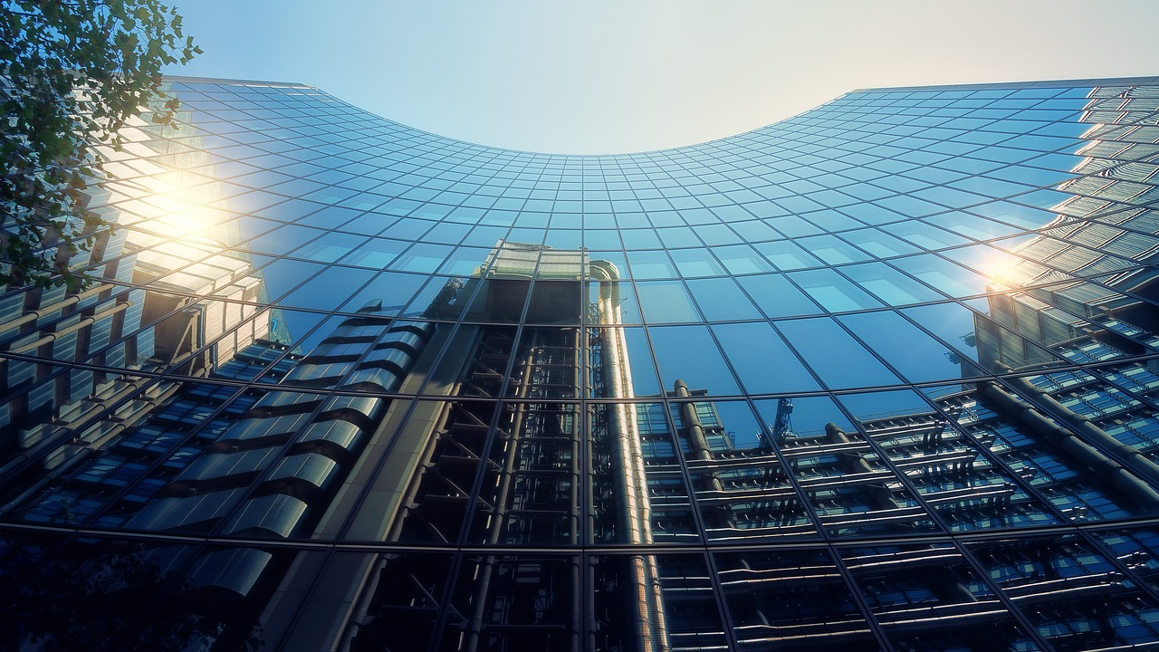 Uma imagem, a apontar para cima, da fachada de um arranha-céus na cidadede Londres. A fachada espelhada reflete os edifícios do outro lado daestrada, um dos quais é a sede da Lloyd's ofLondon.