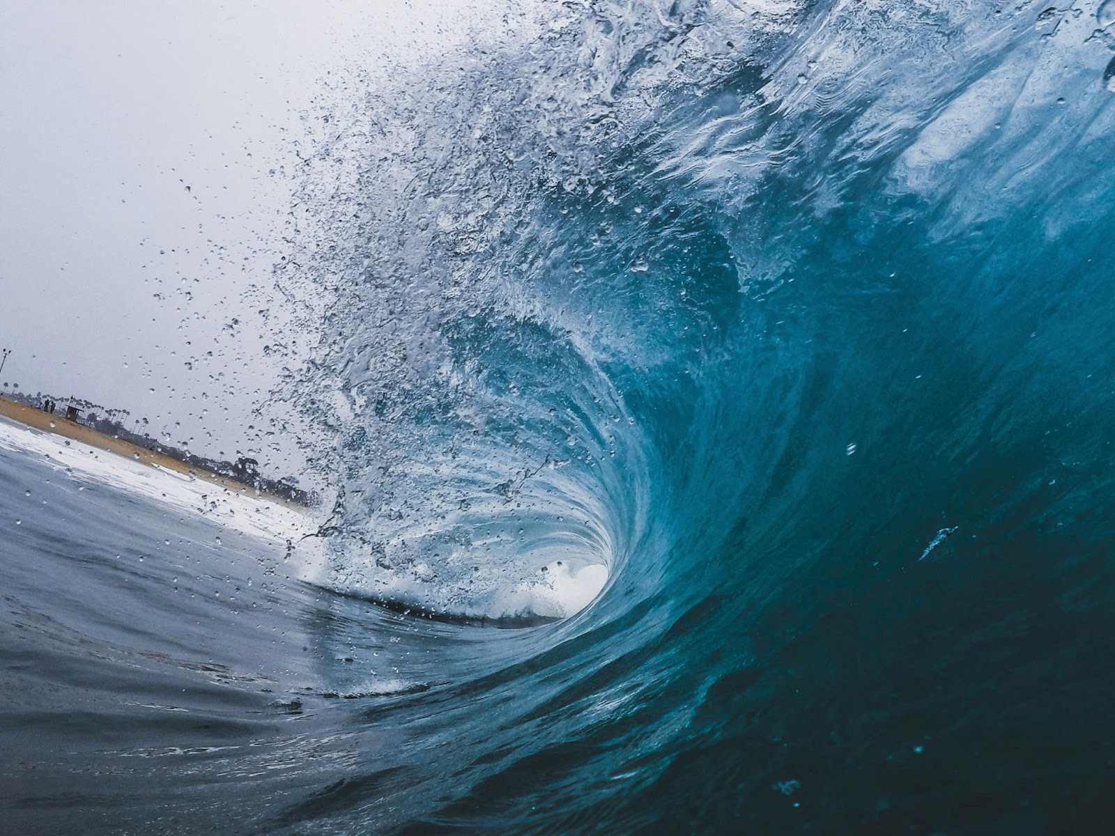 A wave in
Newport Beach, USA La curvatura di un'onda blu cristallina che si infrange verso la costa,con la cresta che spruzzaacqua.